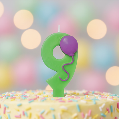 Close up detail of green number 9 birthday candle with purple balloon and ribbon