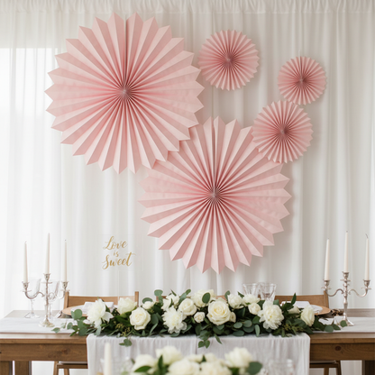 Pink paper fan decorations at a wedding reception table backdrop