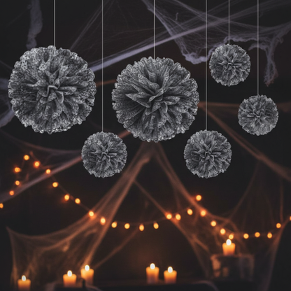 Black and white fluffy tissue paper pom poms hanging from ceiling at Halloween party three sizes with white lace edge detail