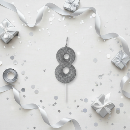 Silver glitter number 8 candle flat lay with silver ribbons gift boxes and silver party decor